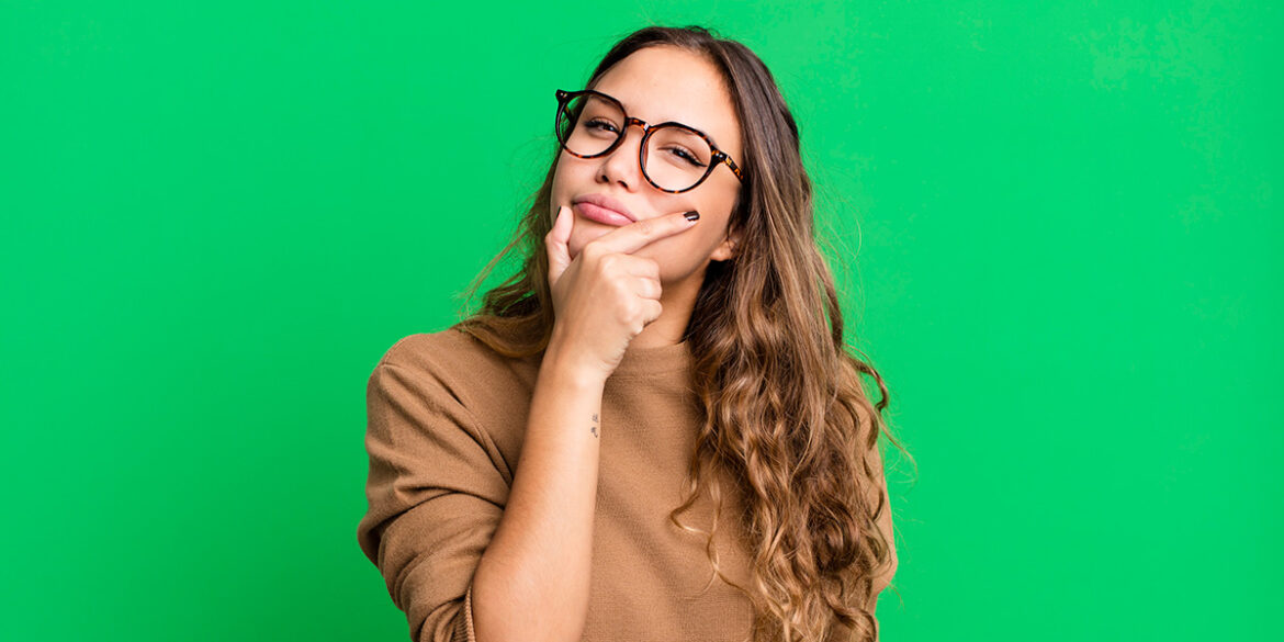 Validação de números - A imagem utilizada na capa do artigo tem uma mulher branca, de cabelo ondulado na cor castranho claro, usando óculos de grau com armação preta, posando para a foto com a mão no queixo fazendo a expressão de dúvida.