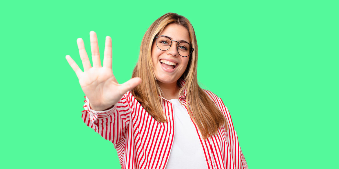 Estratégias de WhatsApp - A imagem que ilustra o tema tem o fundo verde e, no meio, uma mulher branca, de cabelo liso claro, usando um óculos, blusa branca com uma camisa de botão listrada por cima, posando para a foto fazendo o número cinco com a mão.