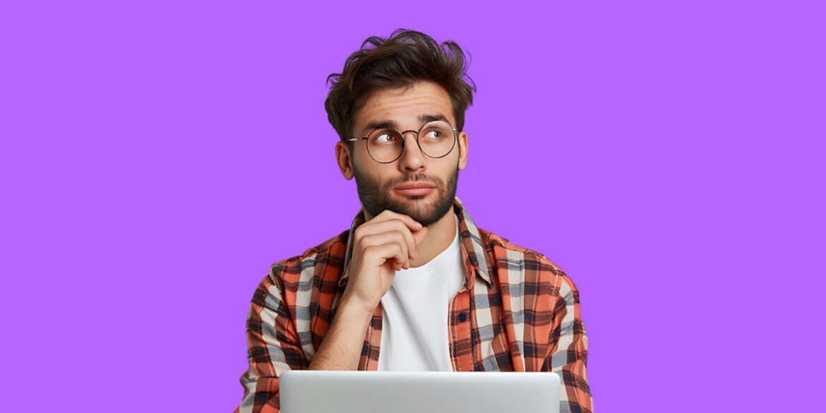 Objeção do preço - A imagem que ilustra o tema tem o fundo roxo e, no meio, um homem, branco, usando uma camisa de botão quadriculada por cima de uma branca, sentado em frente um notebook com a tela aberta. Ele está olhando para o lado e fazendo expressão de pensativo.