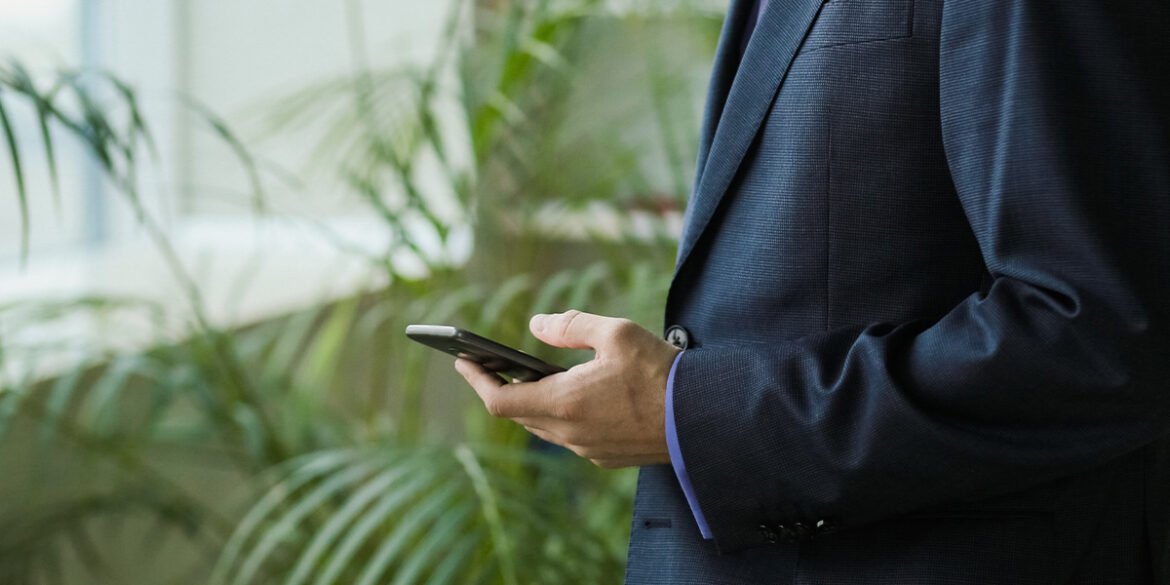 Um homem com o celular na mão.