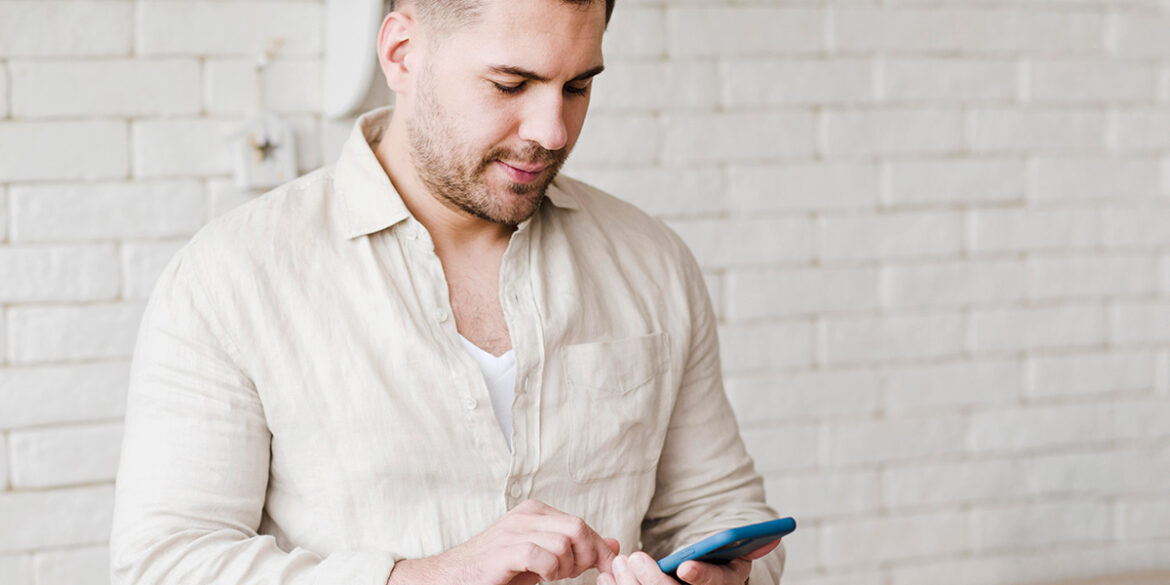 Um homem mexendo no celular.