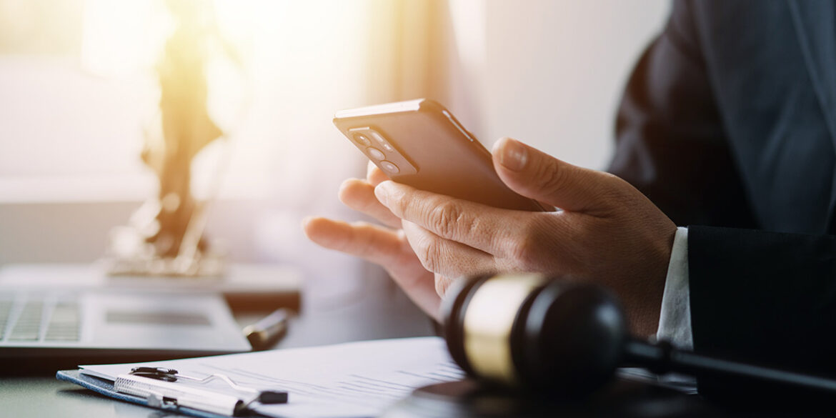 Advogado mexendo no celular dentro do seu escritório.