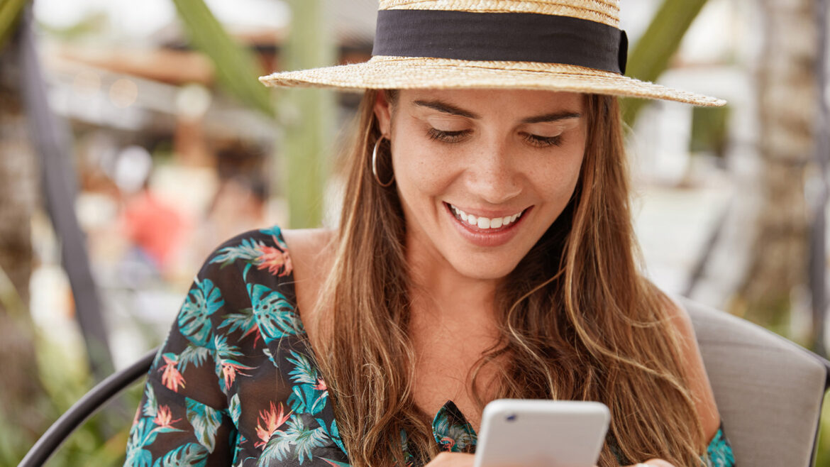 Mulher recebendo mensagem no Whatsapp nas férias de julho
