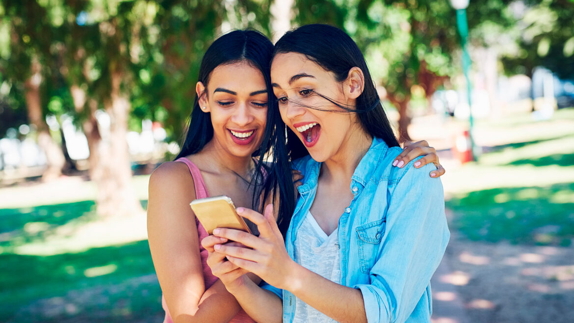 Duas amigas mexendo no WhatsApp no dia do amigo