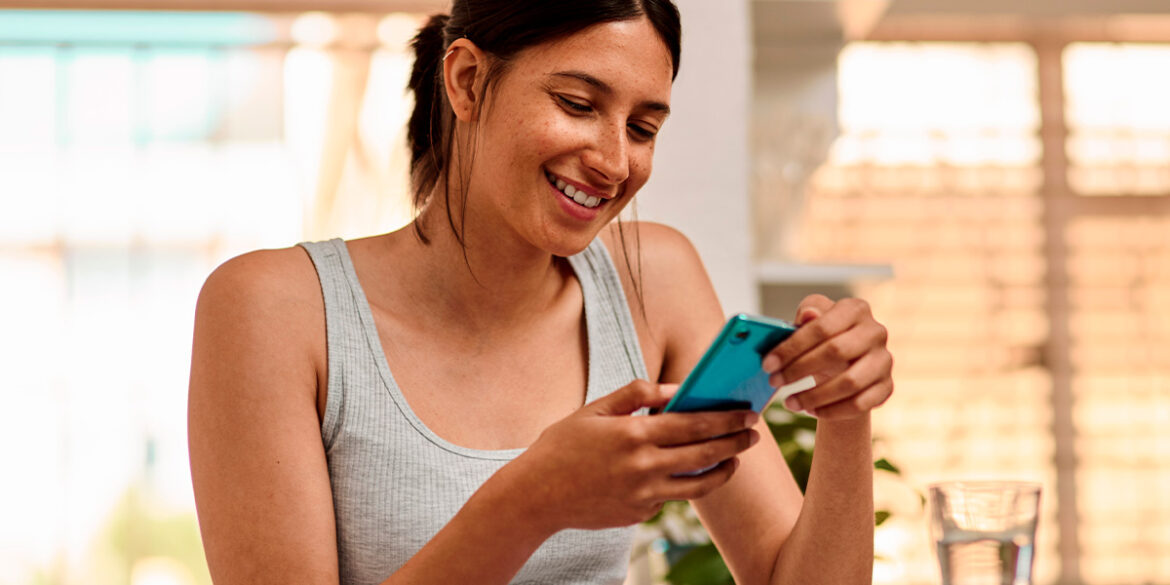 Mulher mexendo no celular e vendo uma publicidade no WhatsApp